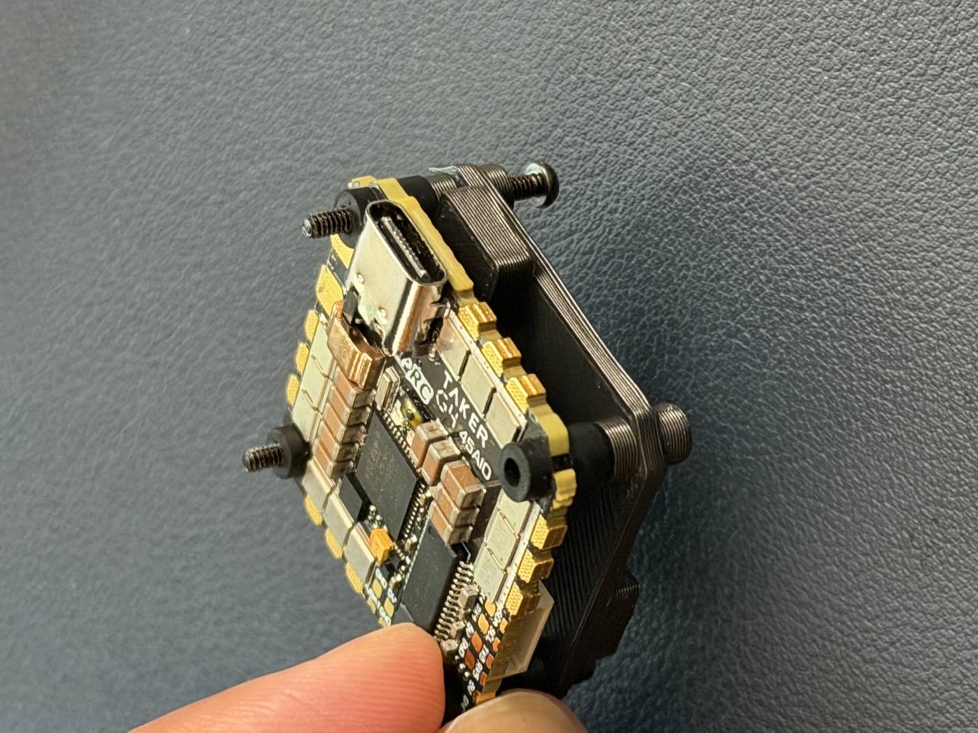 The real GEPRC TAKER G4 AIO flight controller seated in the 3D-printed frame, USB-C port and corner standoffs visible